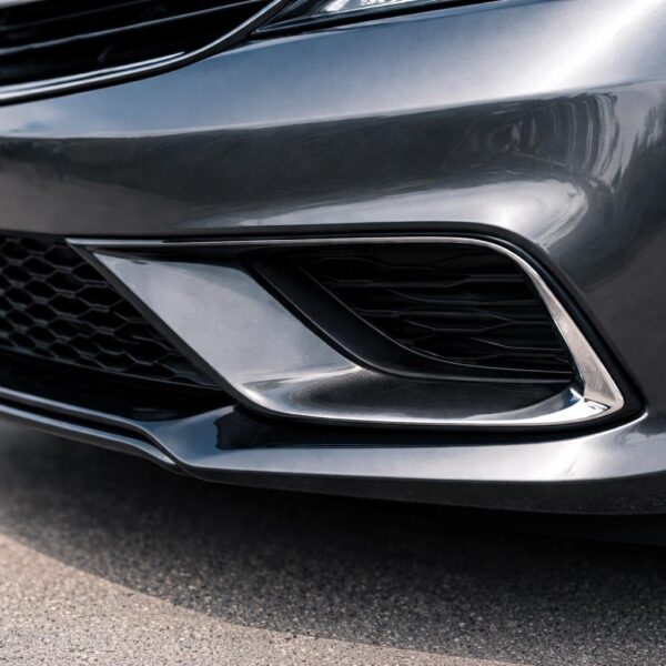 Close-up do para-choque dianteiro de um carro com acabamento brilhante e design moderno.